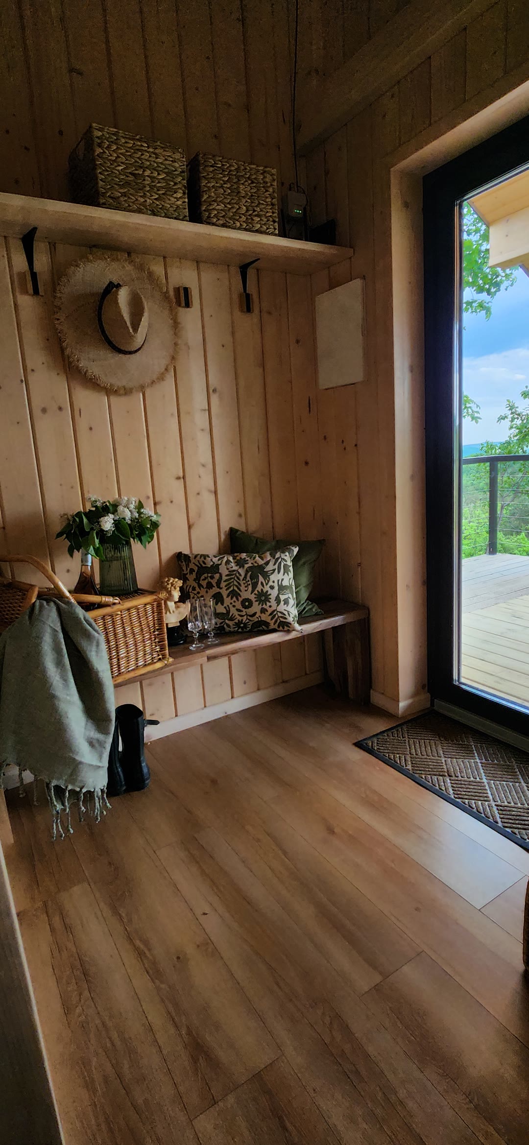 The entrance with a bench, baskets and a glass door to the terrace