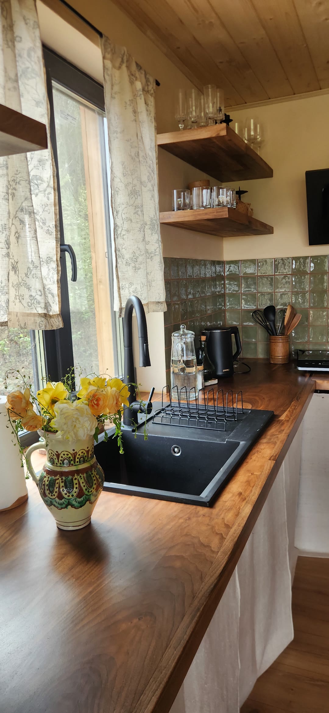 A painted jug of yellow roses by the sink