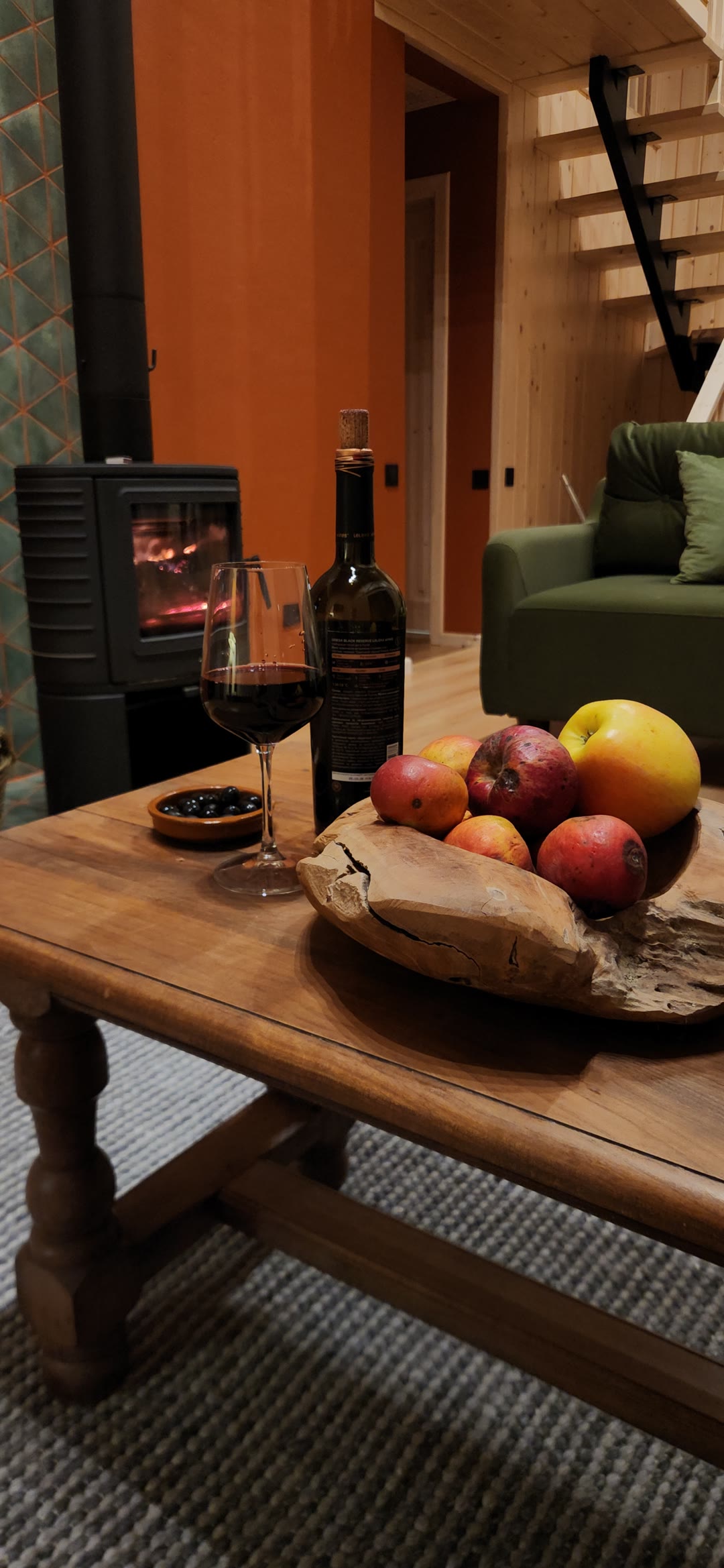 Fire in the fireplace, apples and wine on a wooden table