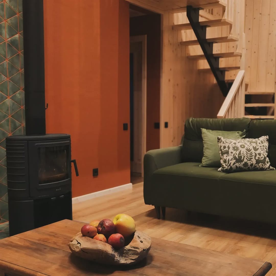 The fireplace by a terracotta wall, a green sofa and timber stairs