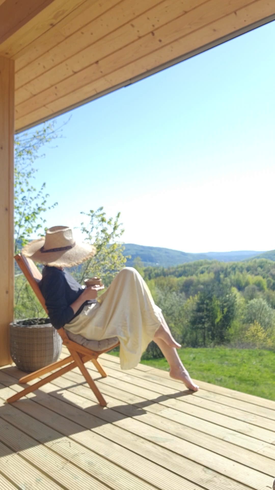 A woman in a straw hat reading in a chair on the terrace