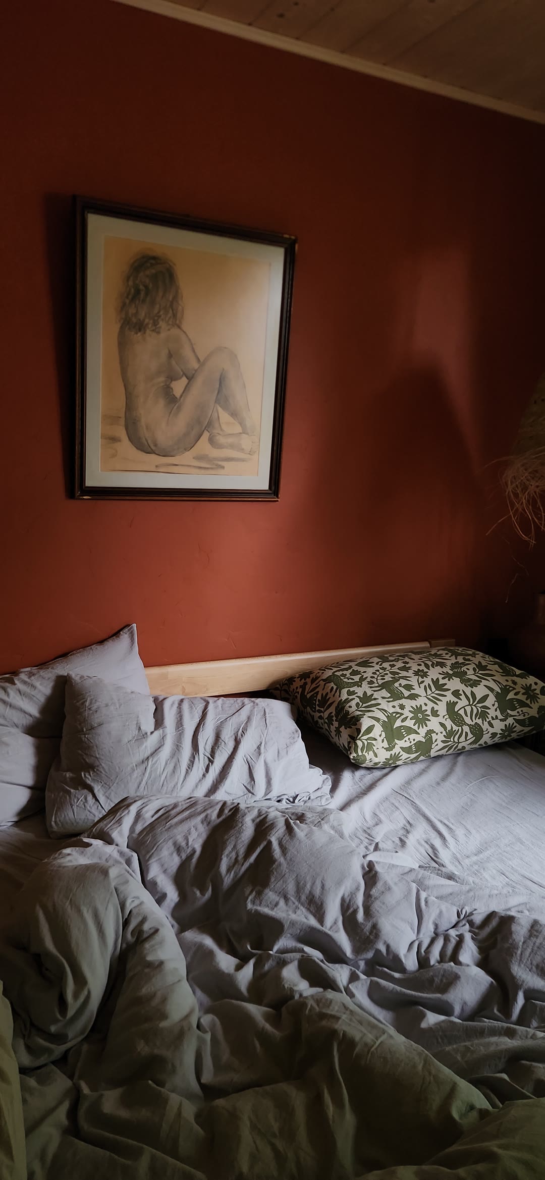 The bed in the morning, rumpled white linen and a green throw