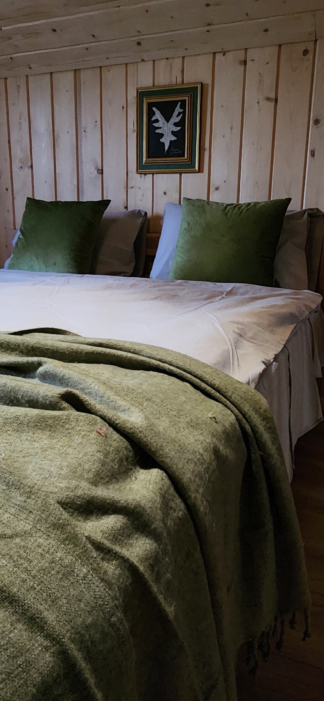 The bed upstairs with green cushions and a throw