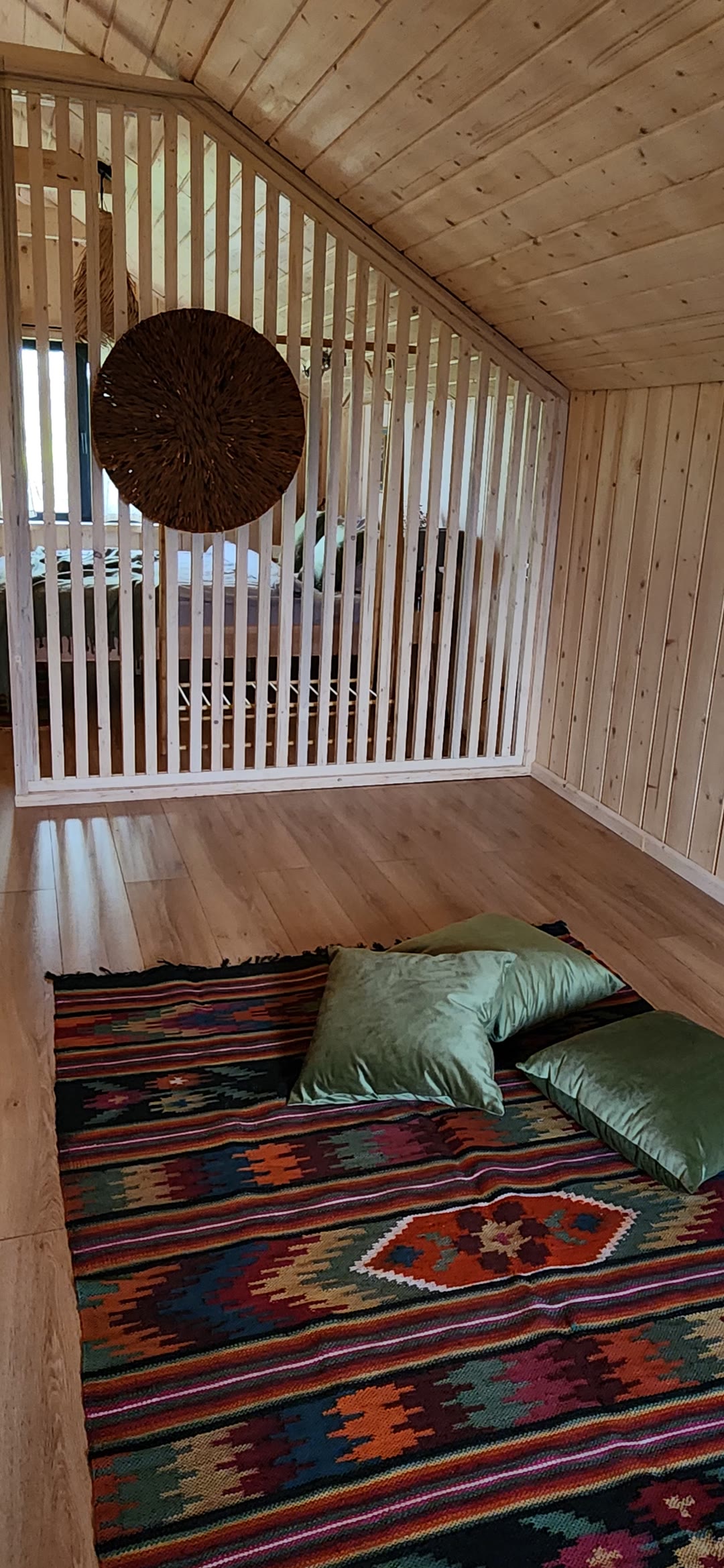 A rug and green cushions by the slatted divider