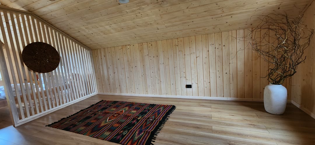 The open space upstairs: slatted divider, a rug and a white vase of branches